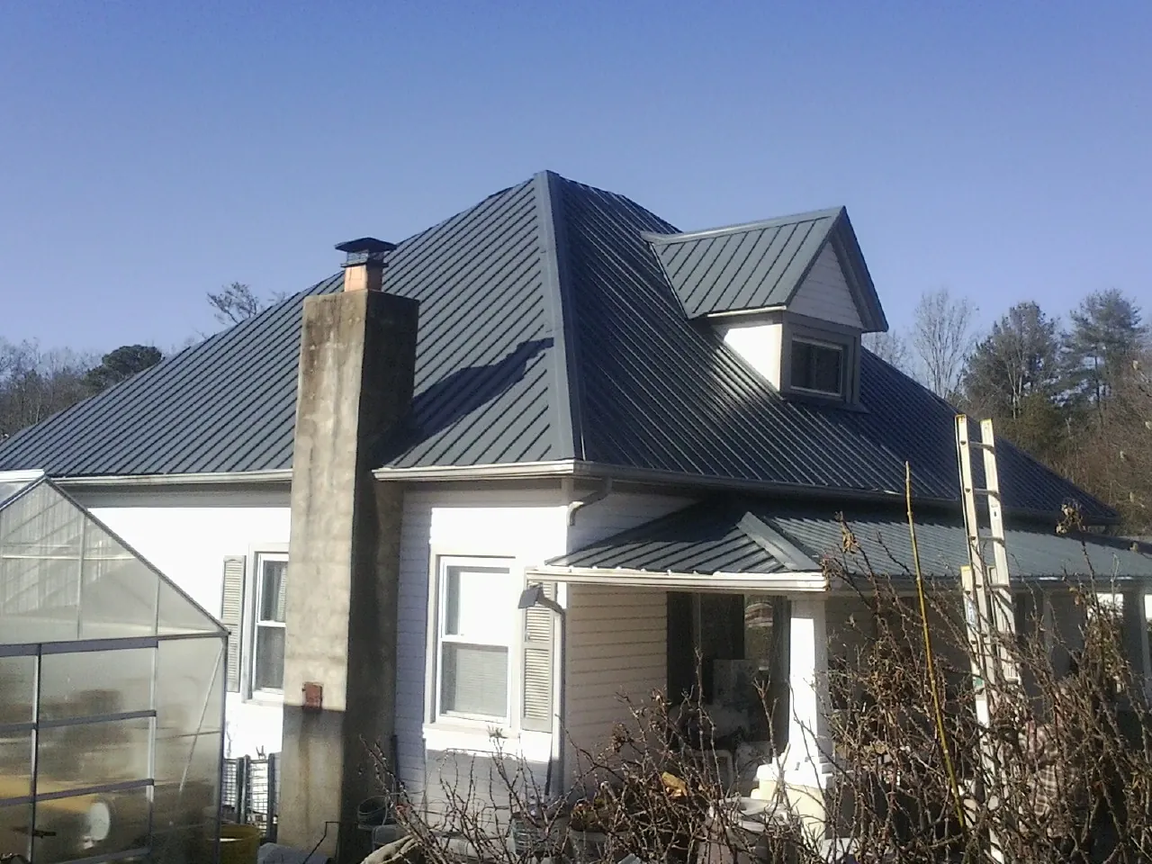 Dark blue standing seam metal roof on a white farmhouse with dormer — Slate & Tile Roof Repair by Roofing Brothers in Madras