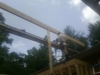 Carpenter setting a ridge beam over a new addition frame — Ice Dam Removal by Roofing Brothers in Madras
