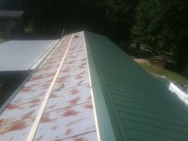Old rusted panels beside newly installed green metal roofing — Wind Damage Roof Repair by Roofing Brothers in Madras