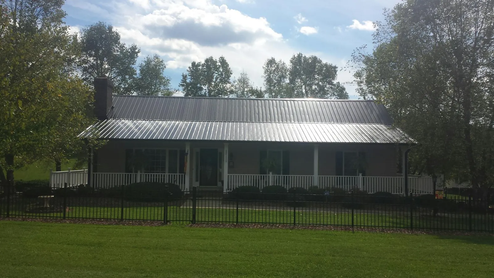 Gray metal roof on a brick ranch with a full width front porch — Gutter Guard Installation work by our crew in Madras