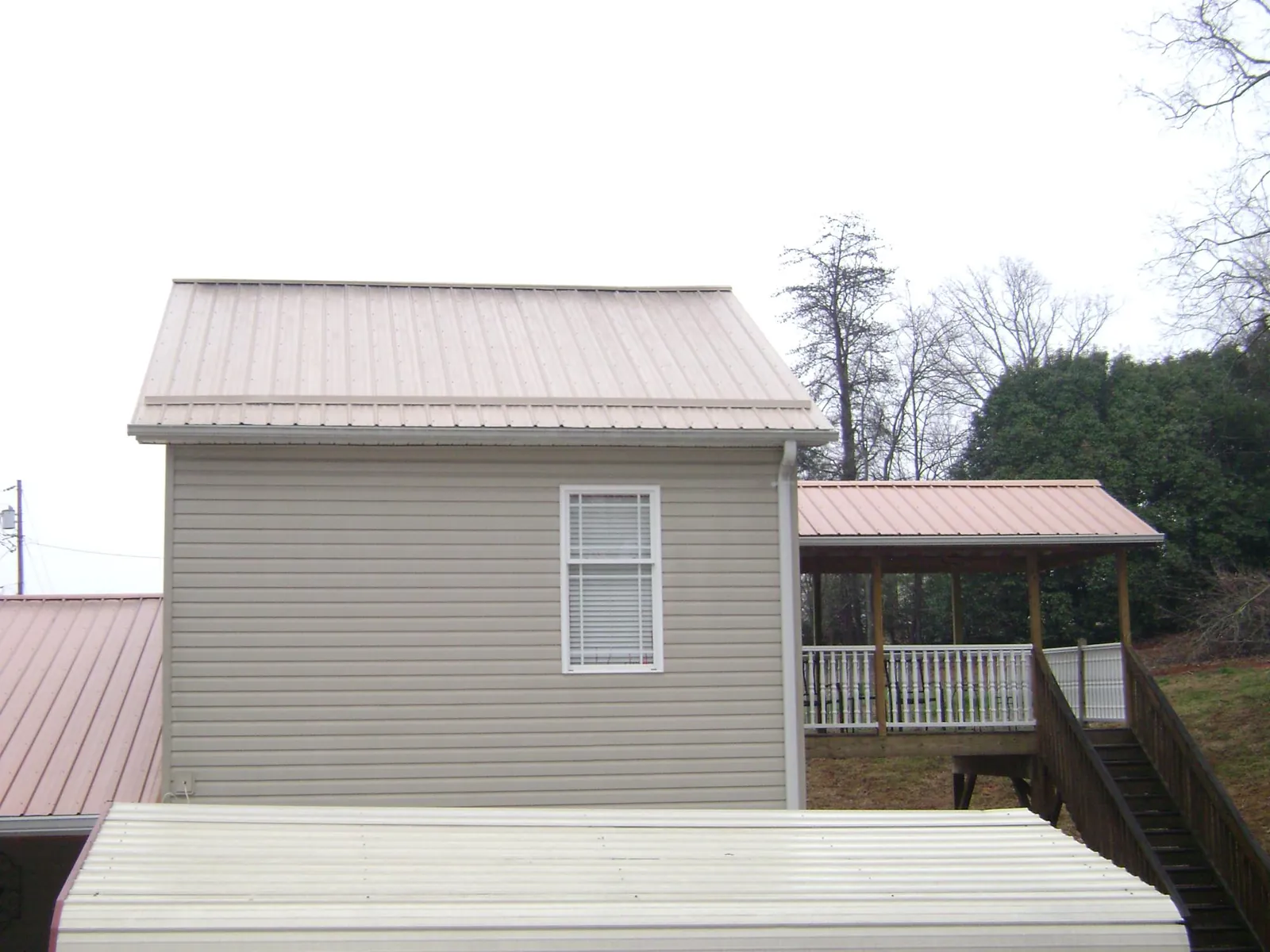 Tan metal roofs on a two story addition and attached porch, from a Roof Replacement job in Madras