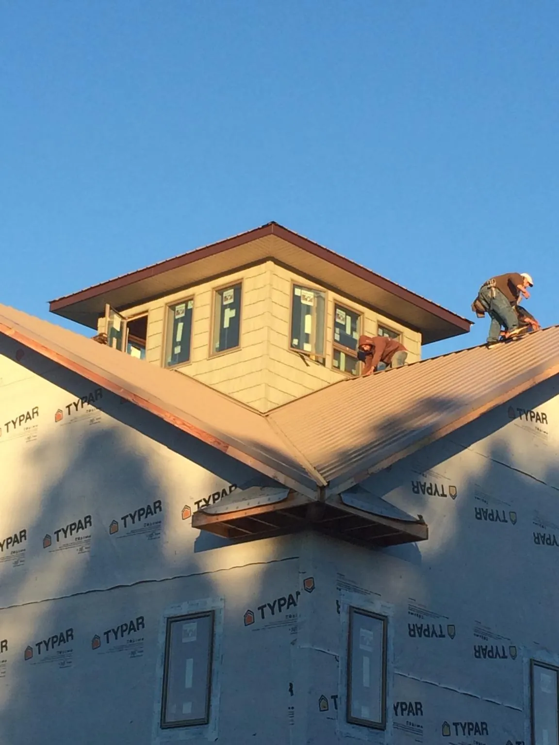 Roofers working around a rooftop cupola on a new metal roof at sunset — Roof Waterproofing in Madras by Roofing Brothers